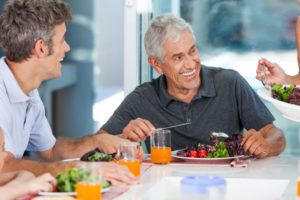 an elderly man smiling and eating with his new dental implants
