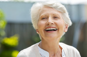 a woman smiling after receiving dentures