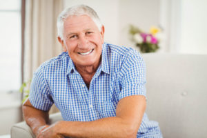 an elderly man smiling after receiving dental implants