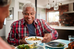 a man with dental implants eating a salad with his family