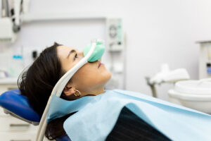 An adult woman sits in a dentist's office wearing a nasal mask to inhale nitrous oxide. Dentist fear concept. Feeling of relaxation with laughing gas