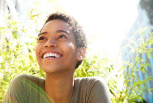 young female smiling brightly outside while basking in the sun